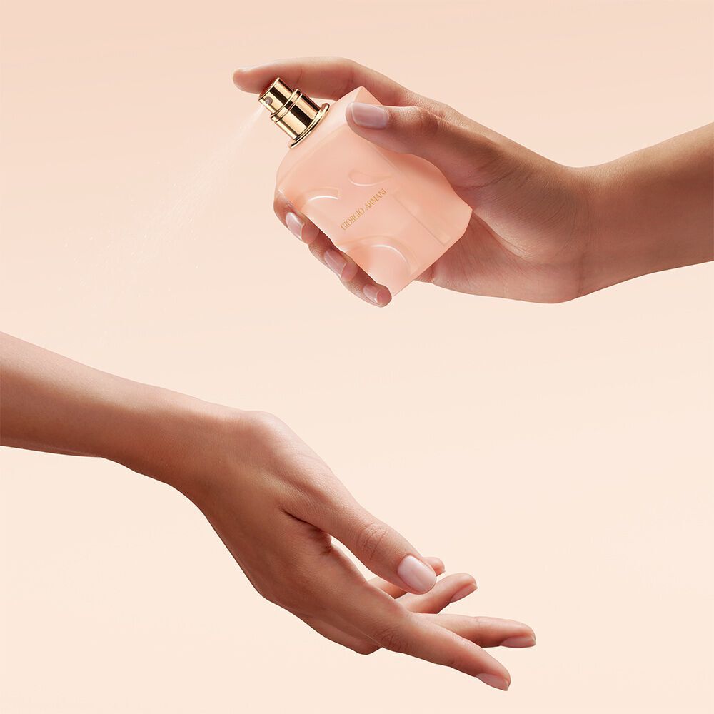 Hand spraying Giorgio Armani Si Nude Bloom perfume onto the wrist.