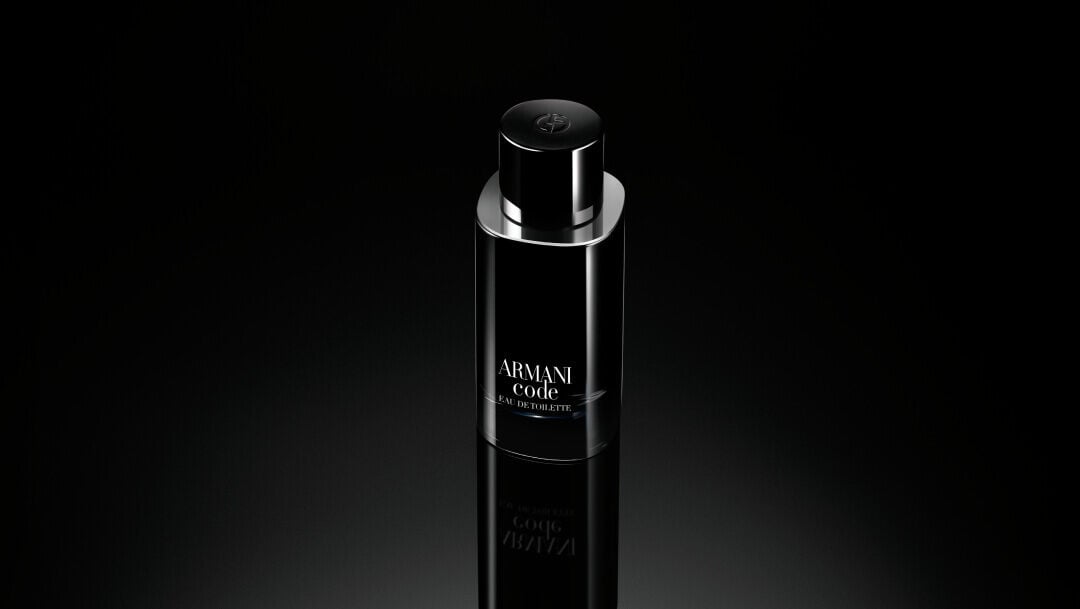 A sleek, glossy black bottle of ARMANI CODE EAU DE TOILETTE standing upright on a reflective black surface, with the Armani logo embossed on the cap and the product name printed in white on the bottle.